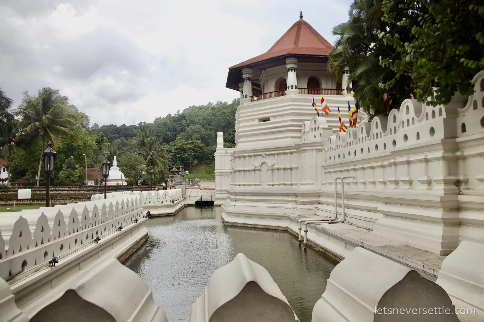 Still moat running along the carved white parapet of the Temple of the Sacred Tooth Relic, the octagonal tower rising above