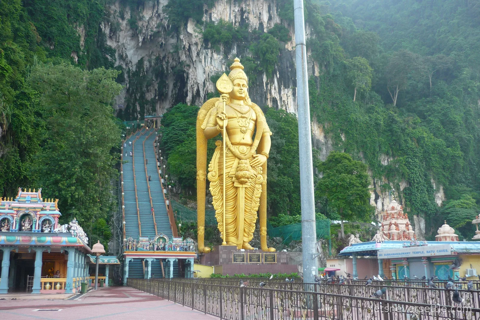 The giant golden Murugan statue beside the long staircase up the limestone cliff at Batu Caves