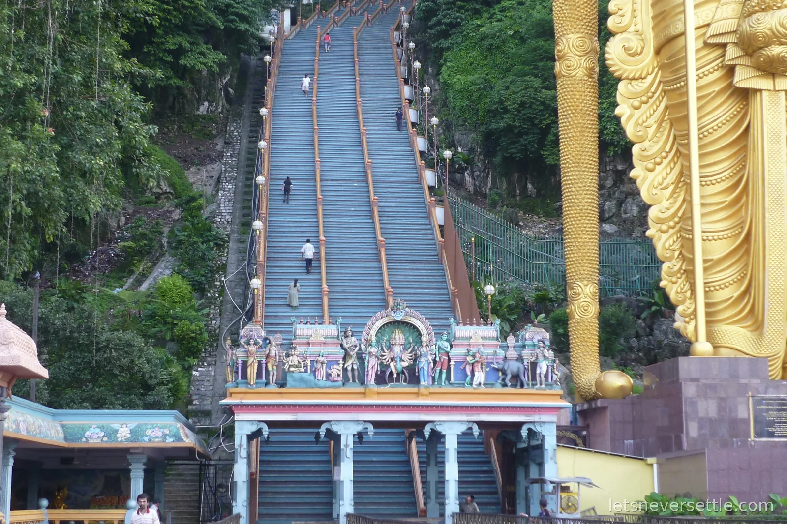 Looking up the steep flight of steps at Batu Caves with the golden statue rising on the right
