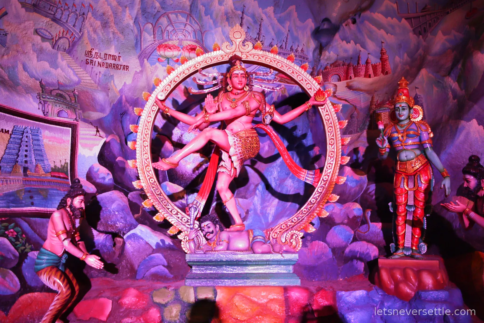 A brightly painted diorama of Hindu deities inside a circular frame in the cave temple at Batu Caves