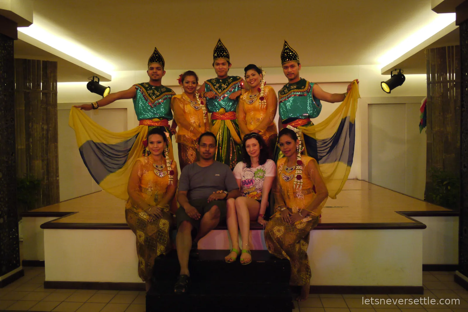 Inga and Dileep on stage with a troupe of Malay dancers in traditional costume after the show
