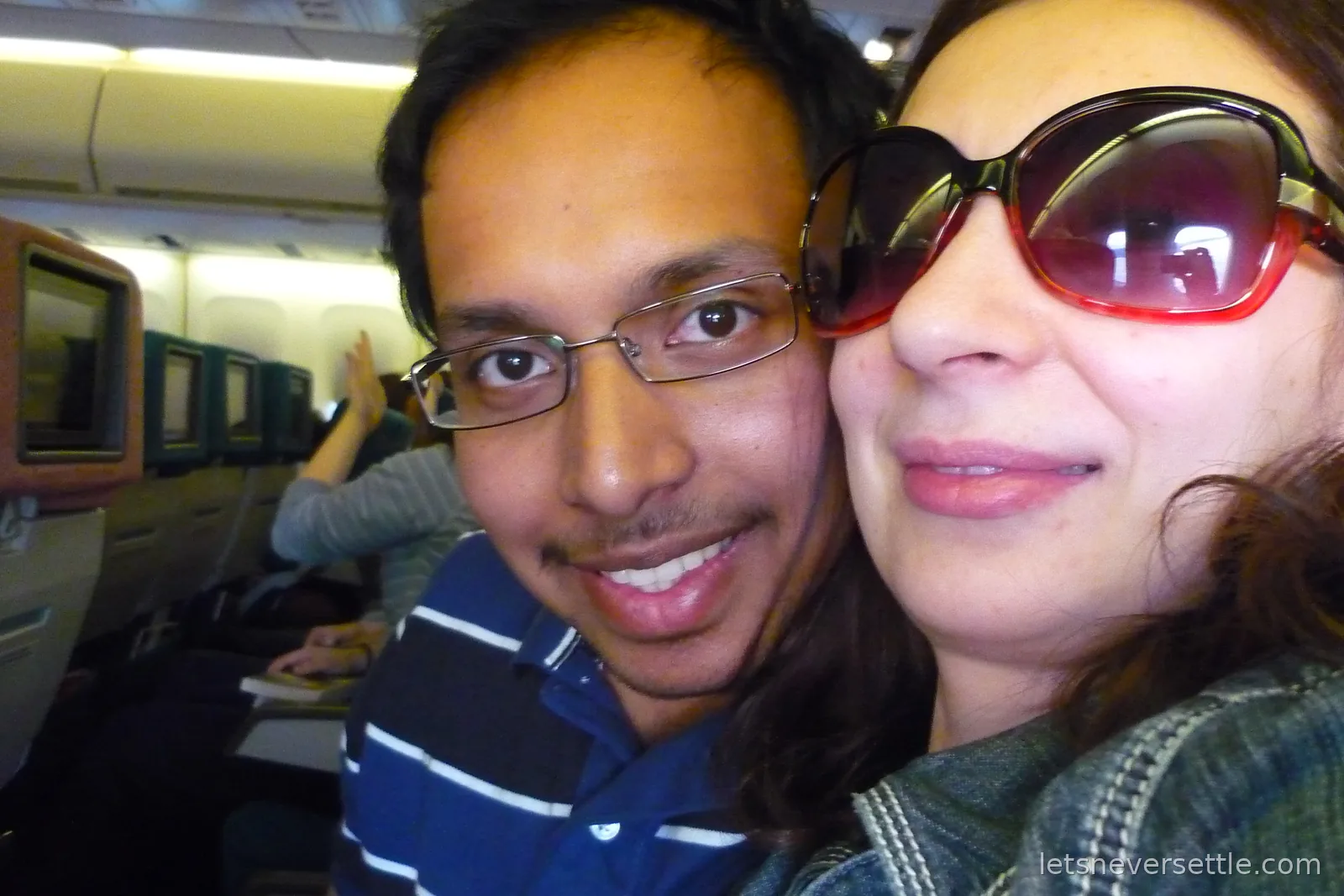 Inga and Dileep smiling in their seats on the flight out to Malaysia