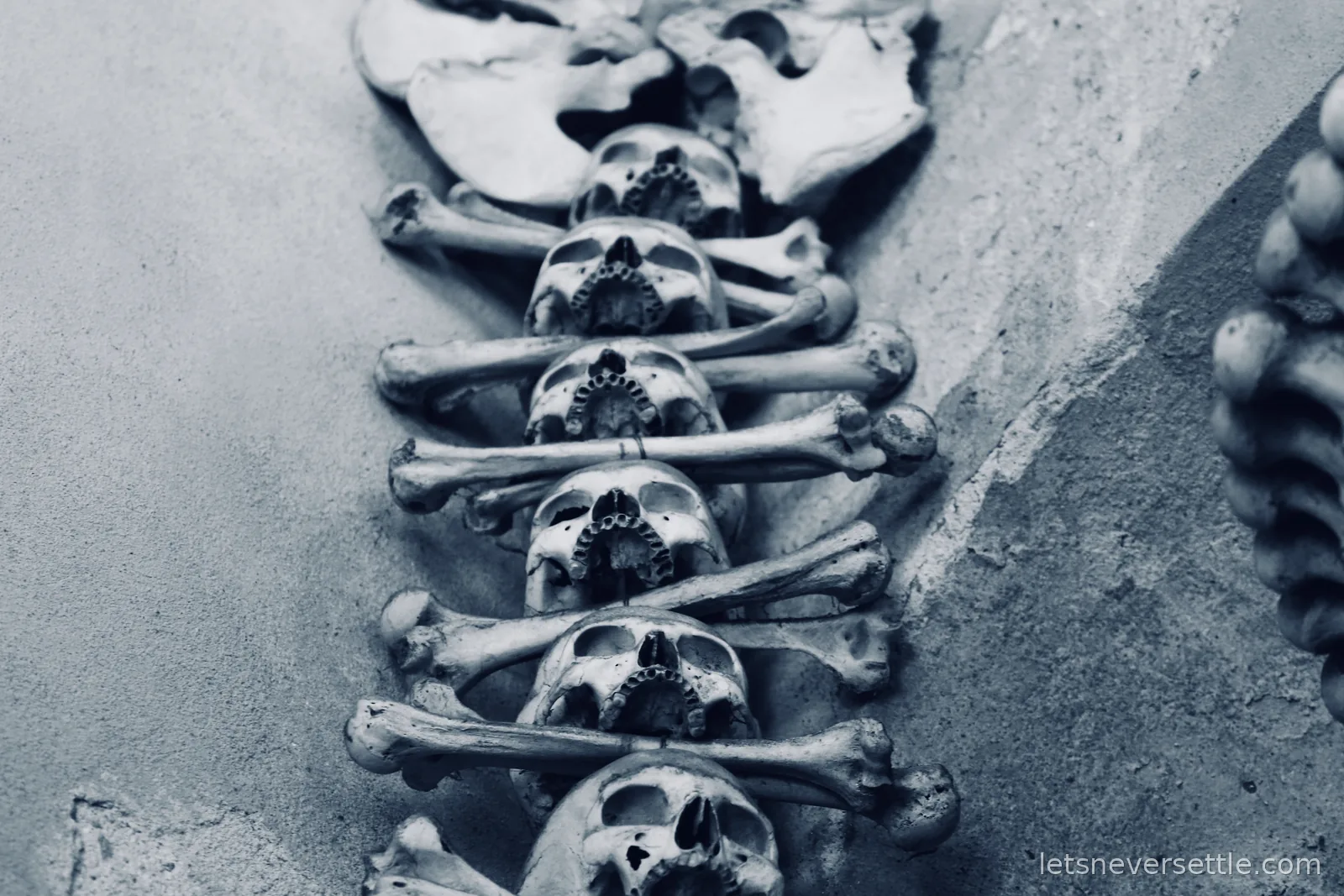 Close-up of a column of skulls, each resting on a pair of crossed long bones, inside the Sedlec Ossuary