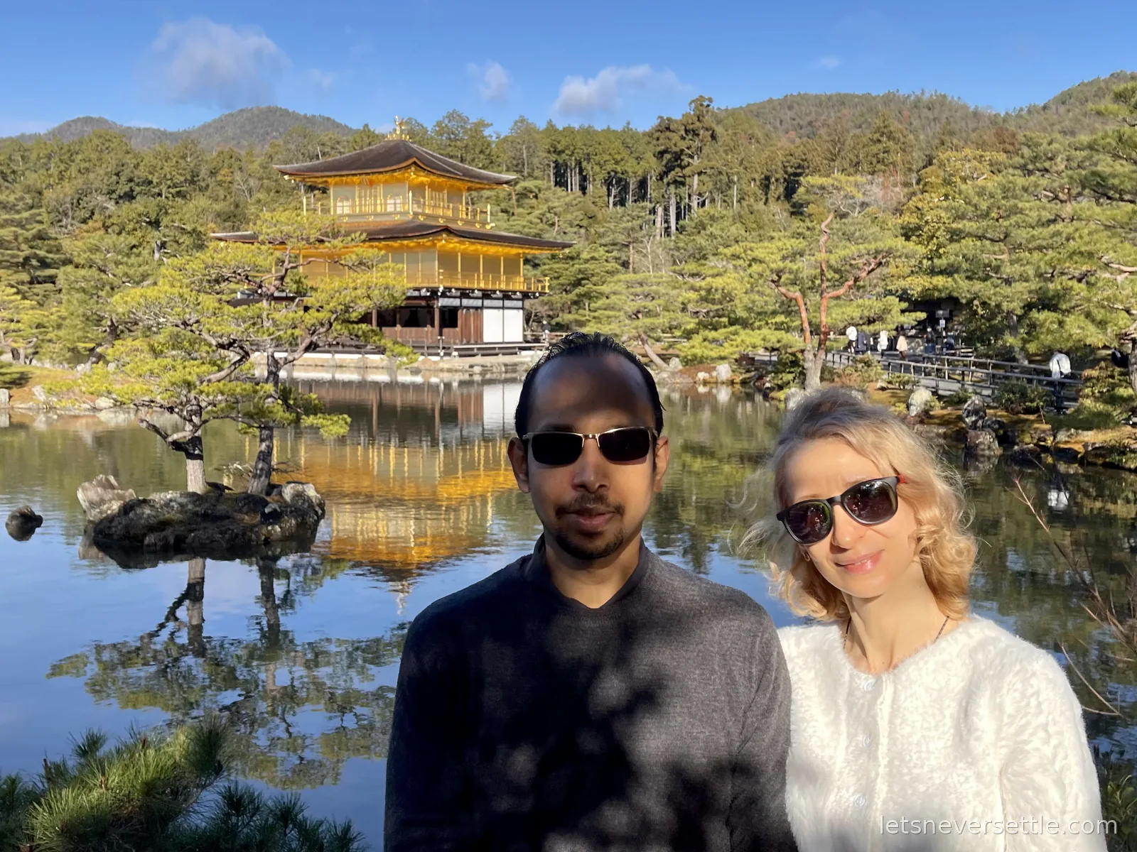 Inga and Dileep in front of the gold Kinkaku-ji pavilion and its reflection in the pond under a blue winter sky