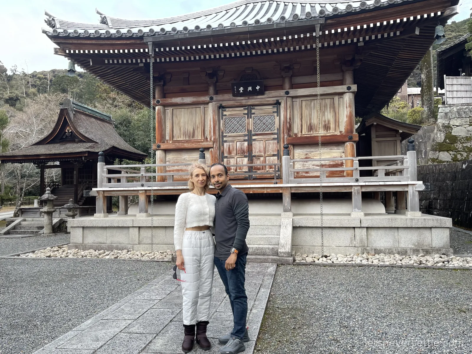 Inga and Dileep standing in front of a weathered wooden temple hall on the stone-covered grounds of Kiyomizu-dera