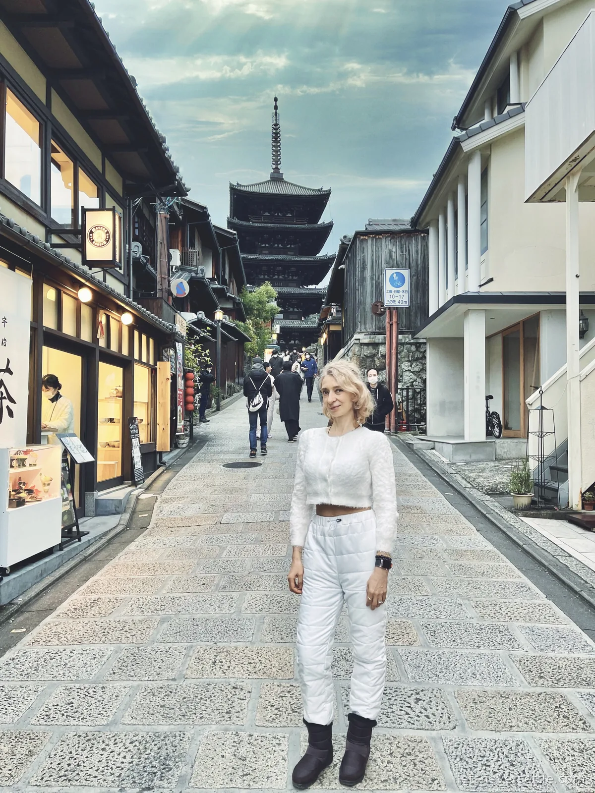 Inga in white standing on a sloping stone-paved lane leading up to the five-storey Yasaka Pagoda