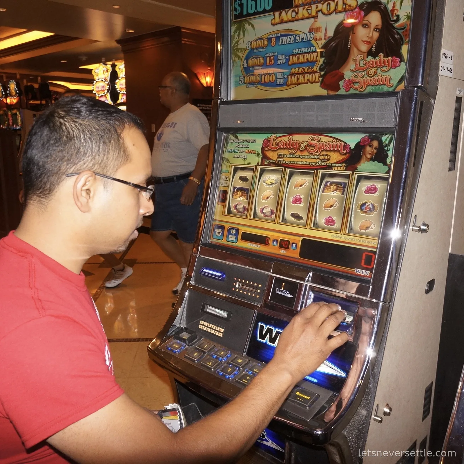 Dileep feeding a card into a Lady of Spain slot machine on a casino floor