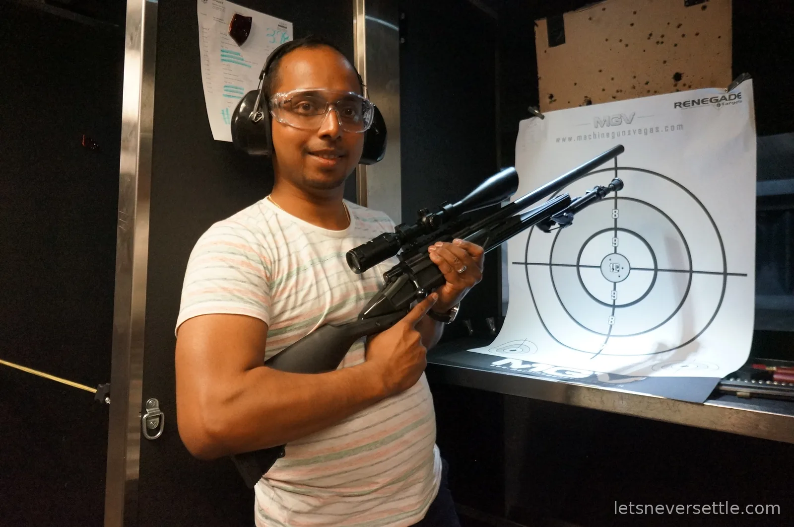 Dileep aiming a scoped rifle at an indoor shooting range