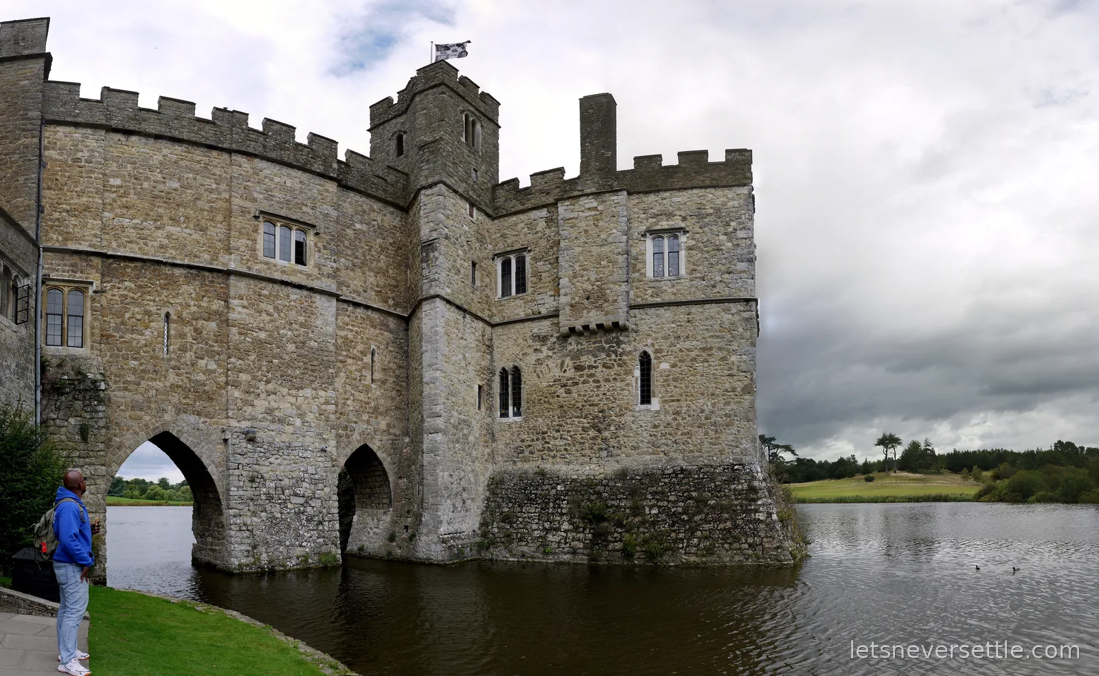 Panorama of the Leeds Castle gatehouse and keep rising straight out of the dark water of the moat under a stormy sky