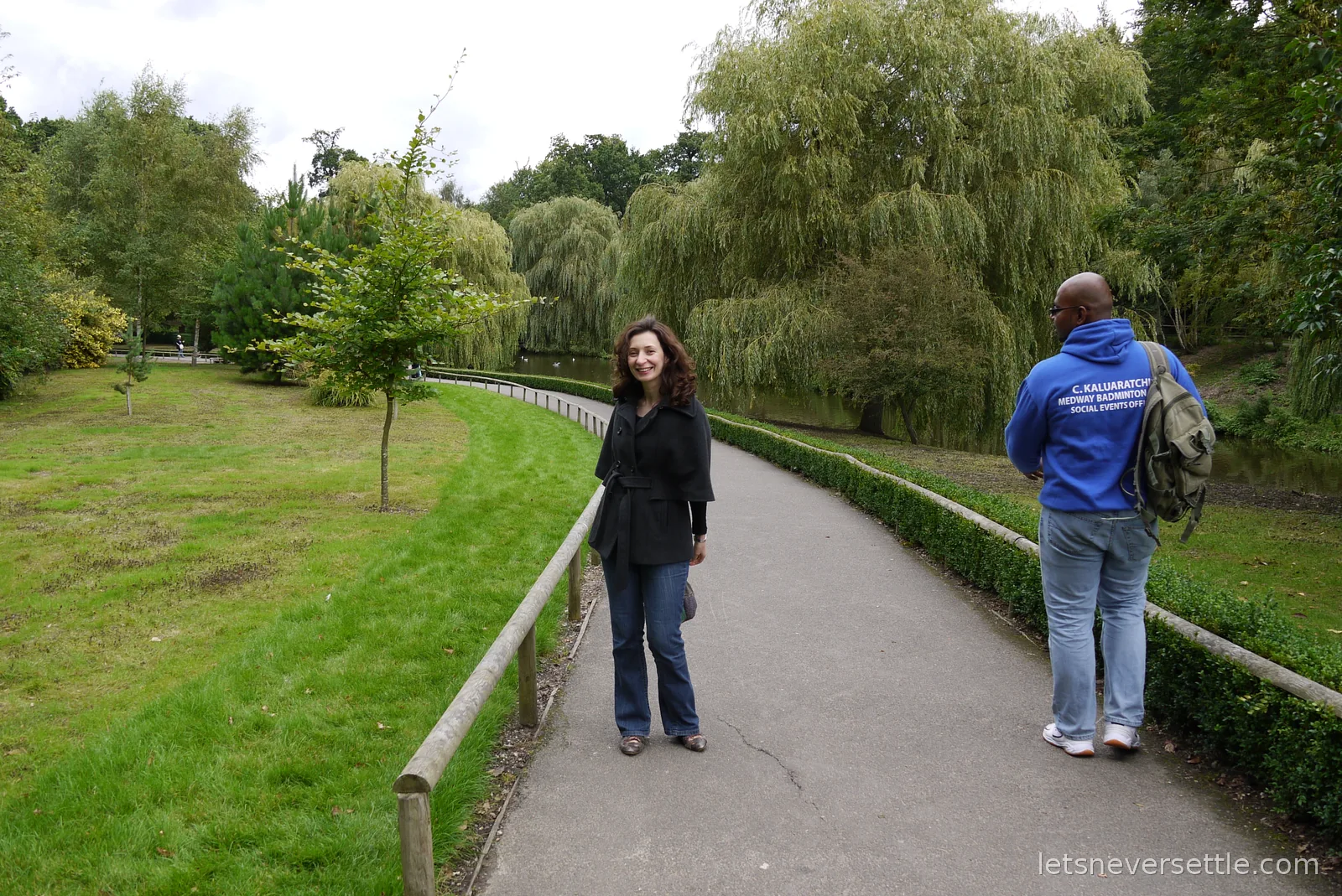 Inga turning to smile on the tree-lined path around the Leeds Castle grounds while Dileep's brother walks ahead with a backpack