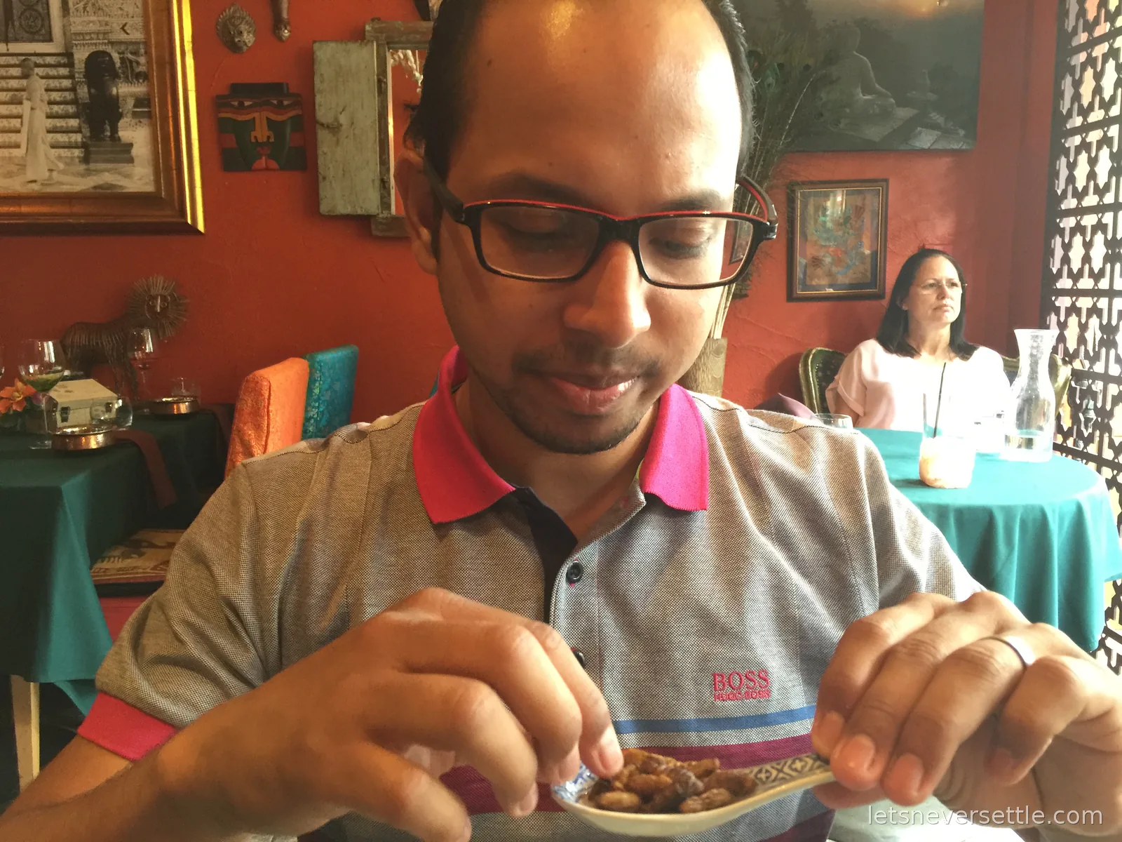 Dileep lifting a spoonful from a small bowl of the insect dish to his mouth at the restaurant table