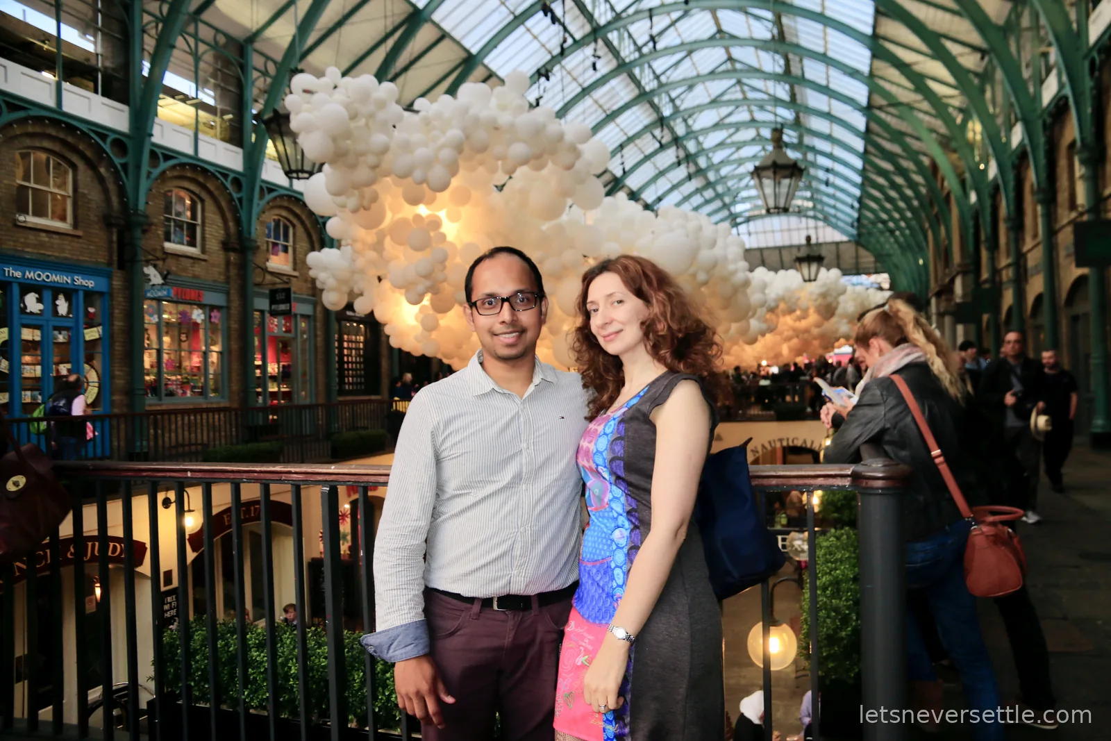 Inga and Dileep in the Covent Garden market hall beneath a huge cloud of white balloons filling the glass roof