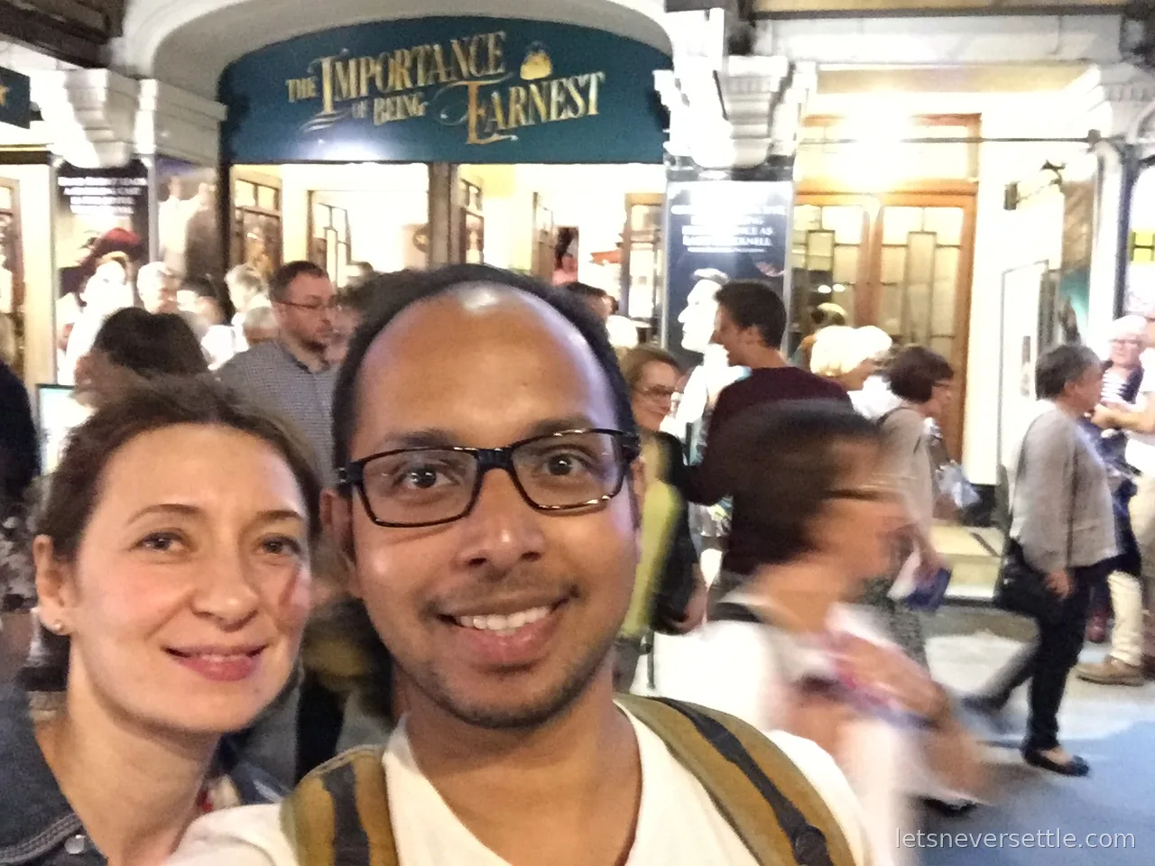 Selfie of Inga and Dileep under The Importance of Being Earnest marquee outside the theatre, crowds behind
