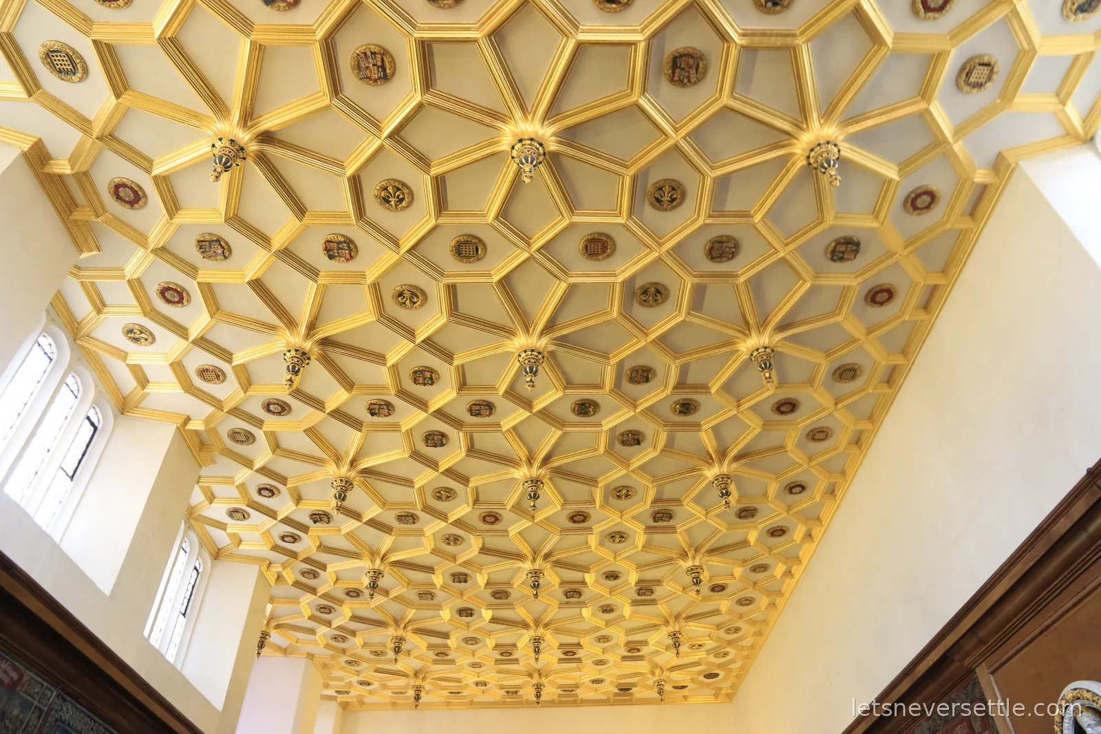 A gilded ceiling at Hampton Court Palace, deep gold coffers studded with painted heraldic bosses