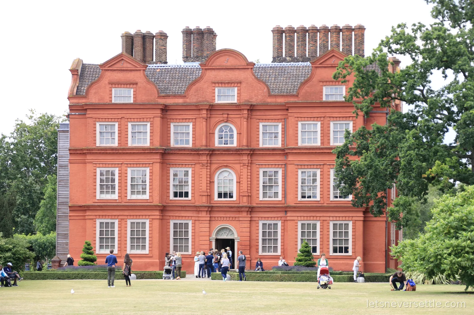 The red brick Dutch-gabled front of Kew Palace with white sash windows and a lawn in front
