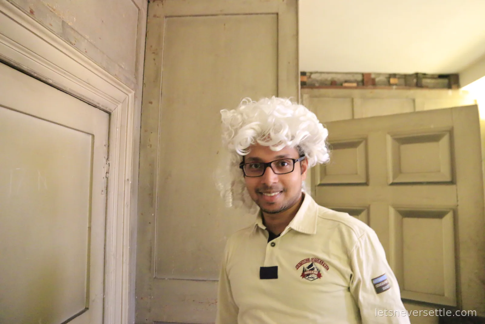 Dileep grinning in a white powdered Georgian wig in a dim room at Kew Palace