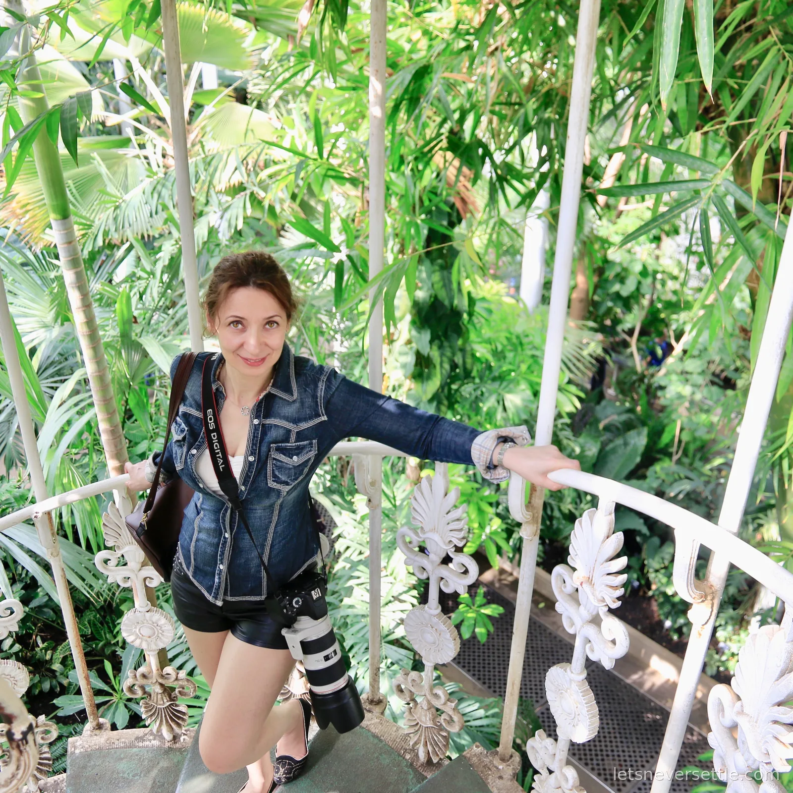 Inga on a white spiral staircase winding up between palm fronds inside the Palm House at Kew Gardens