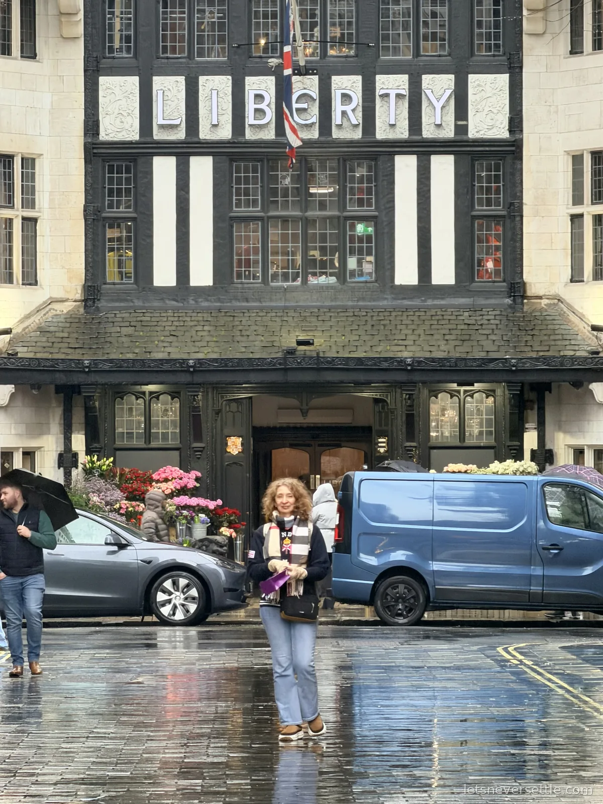 Inga standing on the wet cobbles outside the main entrance of Liberty, buckets of pink and red flowers banked either side of the doorway