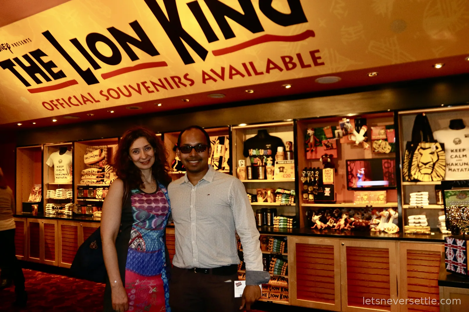 Inga and Dileep at The Lion King official souvenir stand inside a theatre foyer