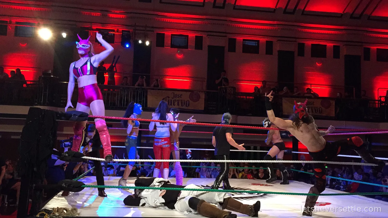 Several masked wrestlers in the ring, one of them mid-air being thrown while the others wait along the ropes