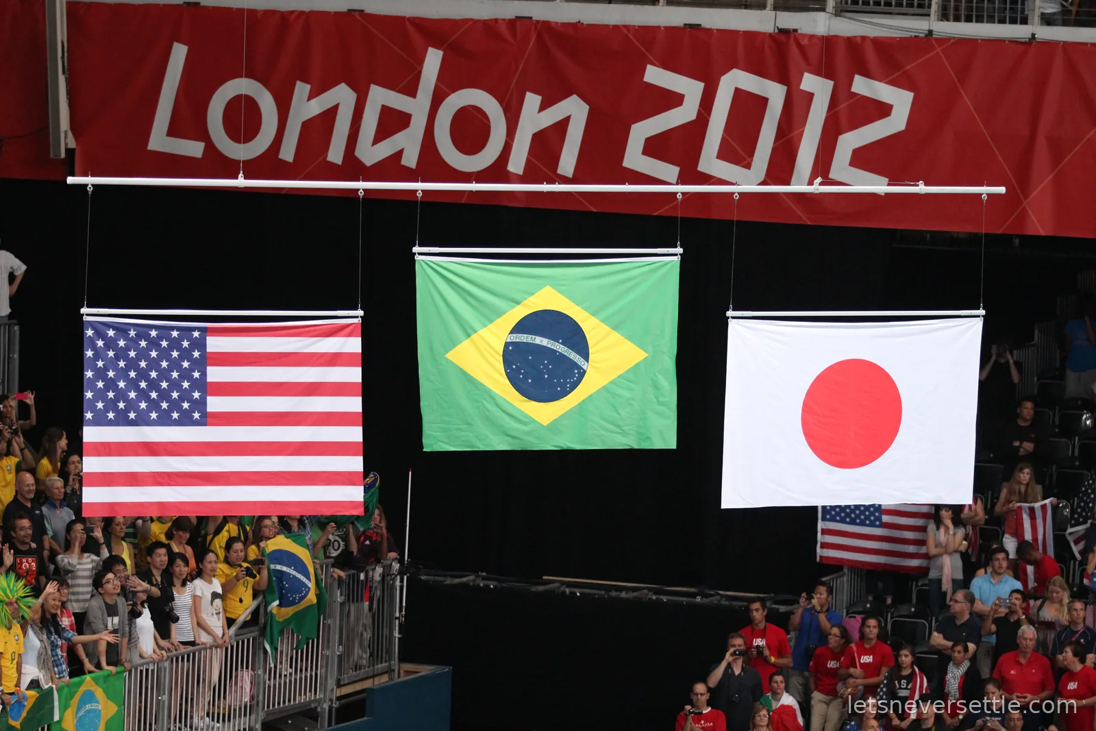 The flags of the USA, Brazil and Japan hoisted under a red London 2012 banner at the volleyball medal ceremony