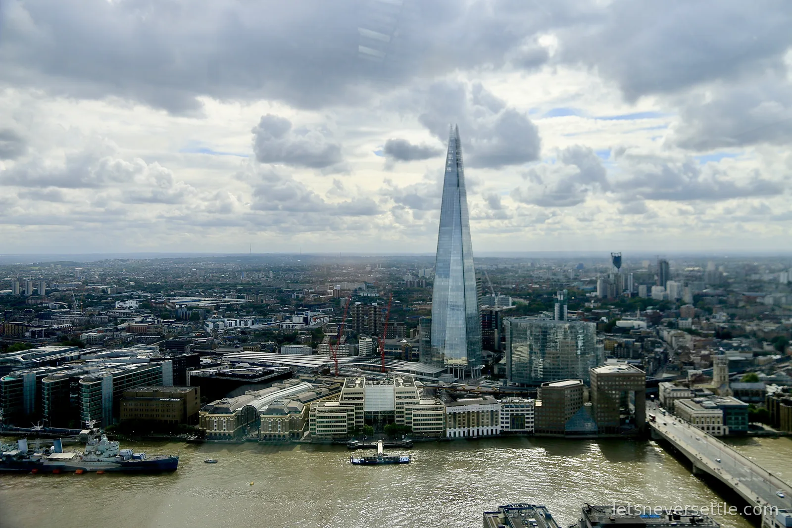View from high up across the Thames to the Shard, with HMS Belfast moored on the river below