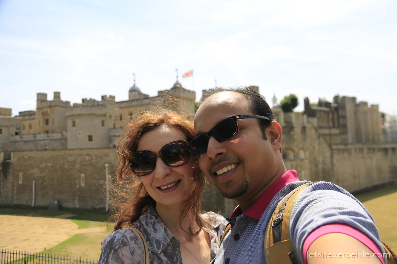 Selfie of Inga and Dileep in sunglasses in front of the walls and White Tower of the Tower of London