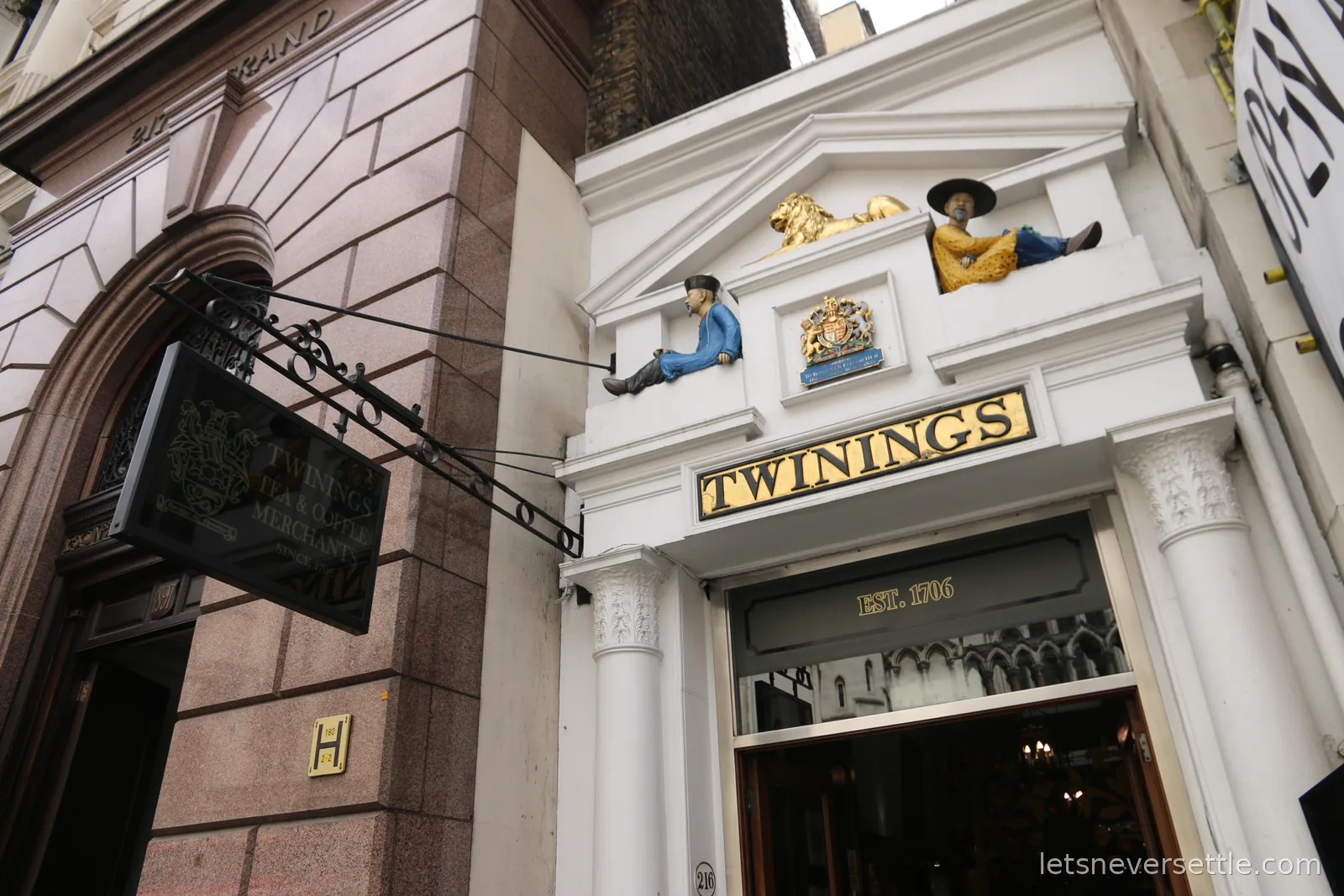 The white Twinings shopfront at 216 Strand with a golden lion and two seated painted figures above the door and Est. 1706 lettered on the glass