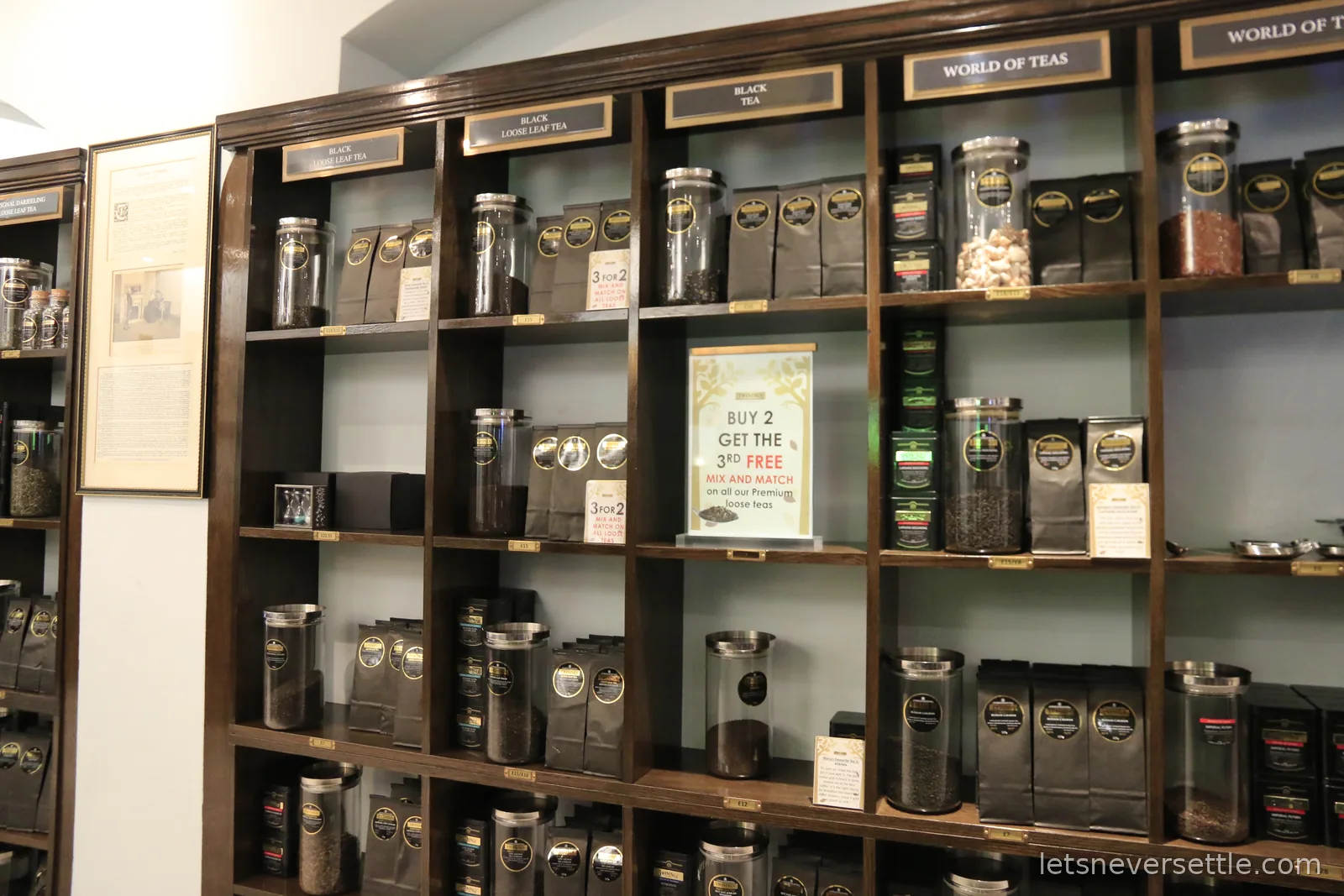 Shelves of labelled glass jars and tins of loose leaf tea under a World of Teas sign inside the Twinings shop
