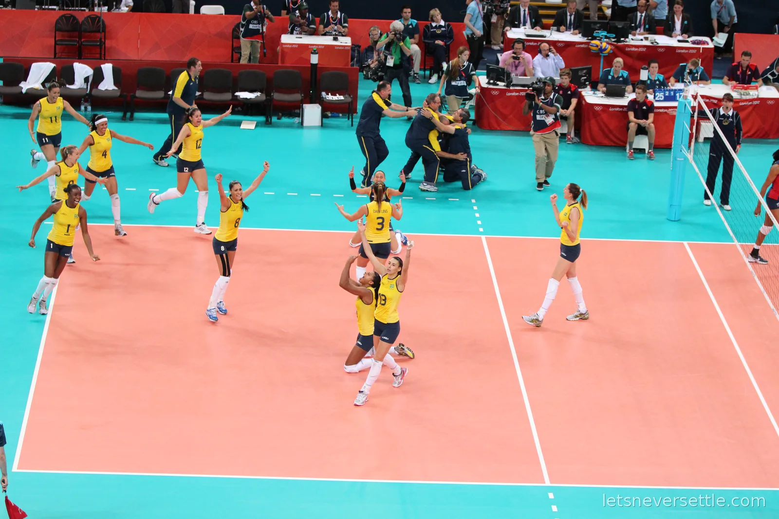Brazil's players in yellow celebrating across the court at the London 2012 women's volleyball final, coaches embracing at the side