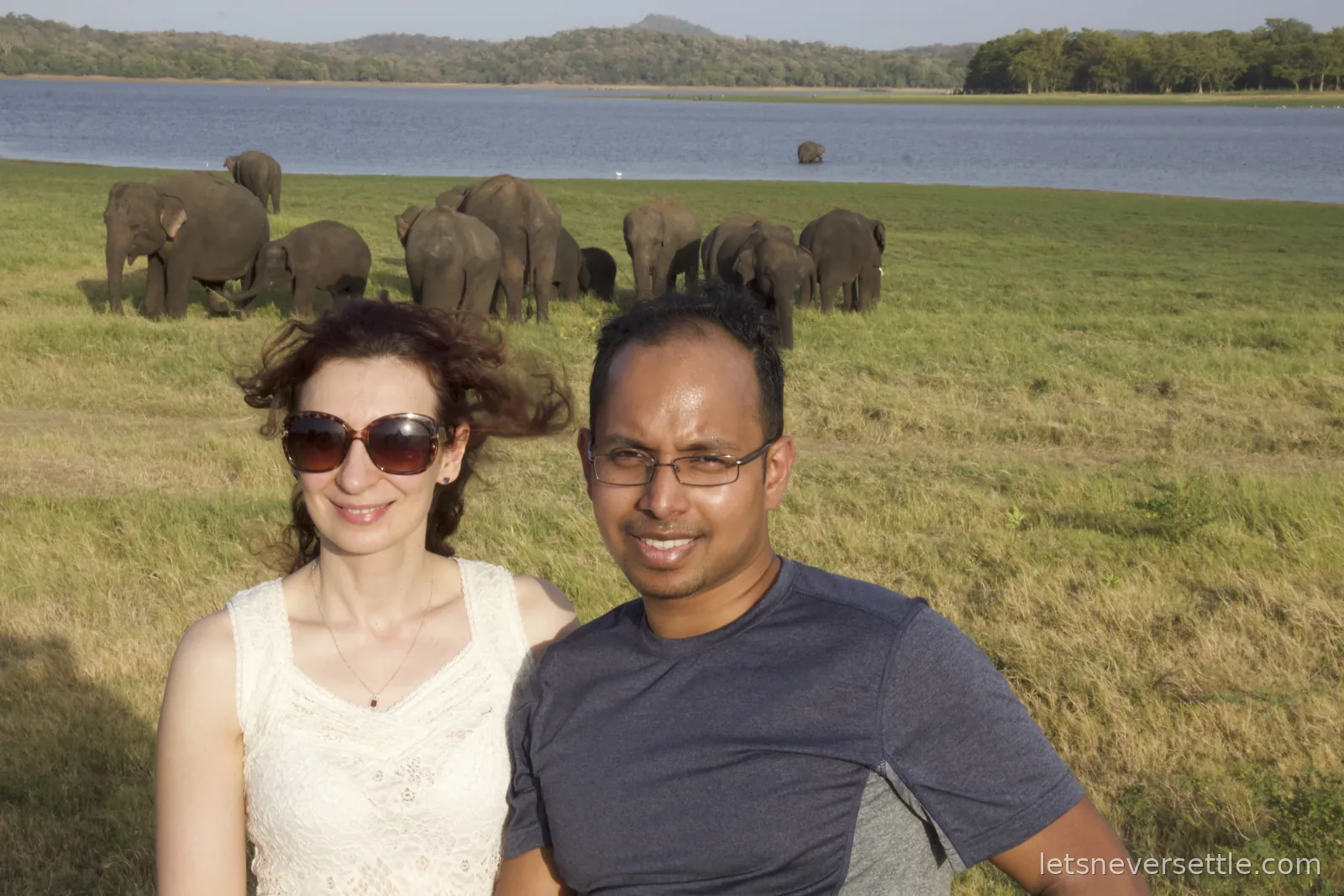 Inga and Dileep in the jeep with a herd of elephants and the Minneriya tank stretching out behind them