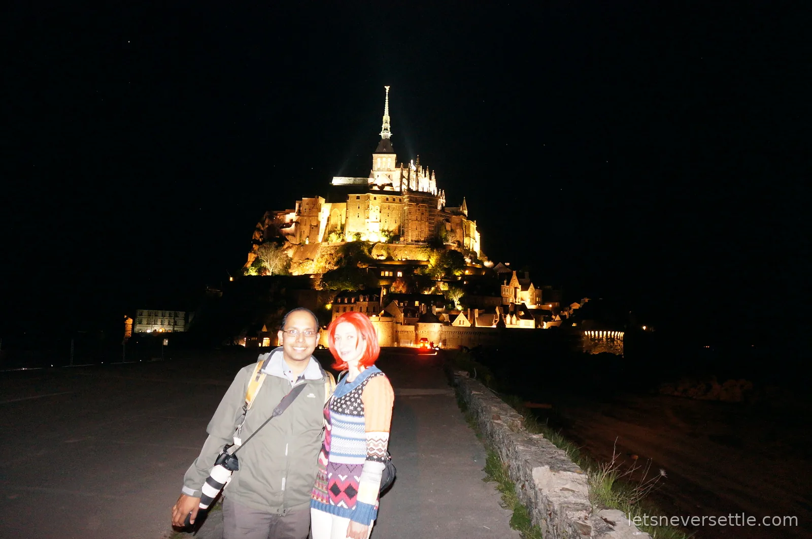 Inga and Dileep at night in front of the floodlit Mont Saint-Michel