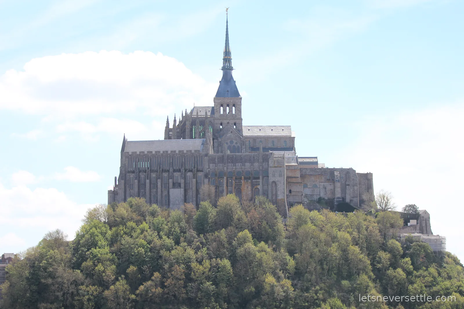 Mont Saint-Michel abbey with its spire rising above the trees on the island