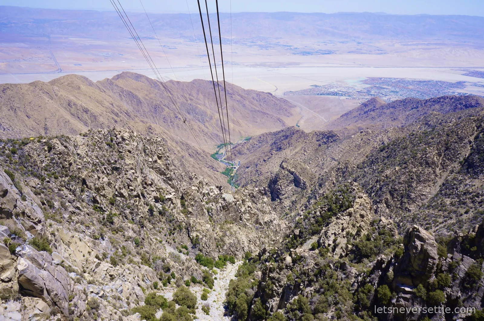 View down the tramway cables over rocky ridges to the flat Coachella Valley floor