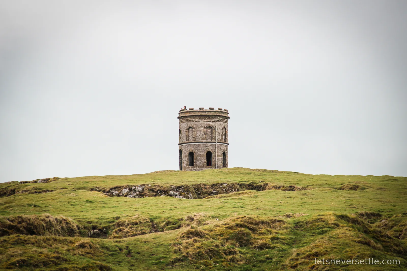 Solomon's Temple, a round castellated stone tower, standing on the grassy limestone hilltop of Grin Low above Buxton
