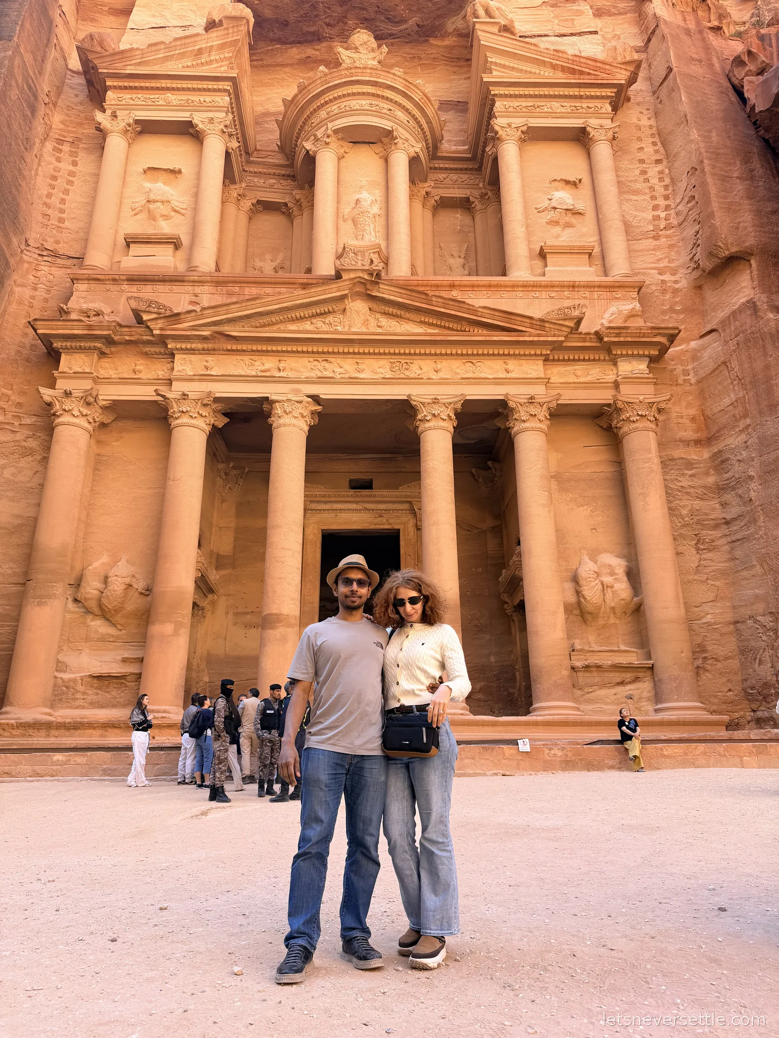 Inga and Dileep standing between the giant columns at the entrance of the Treasury at Petra