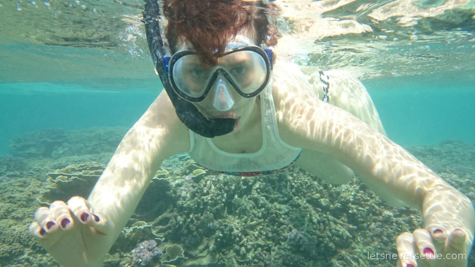Inga snorkelling underwater in a mask, swimming towards the camera over a coral reef