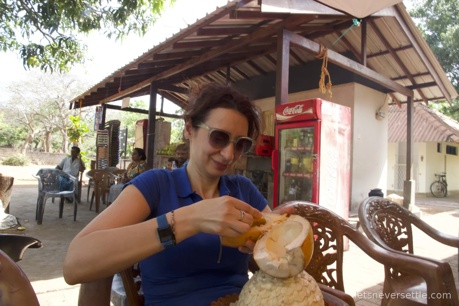 Inga at a roadside stall digging the flesh out of a king coconut with a spoon carved from its own husk