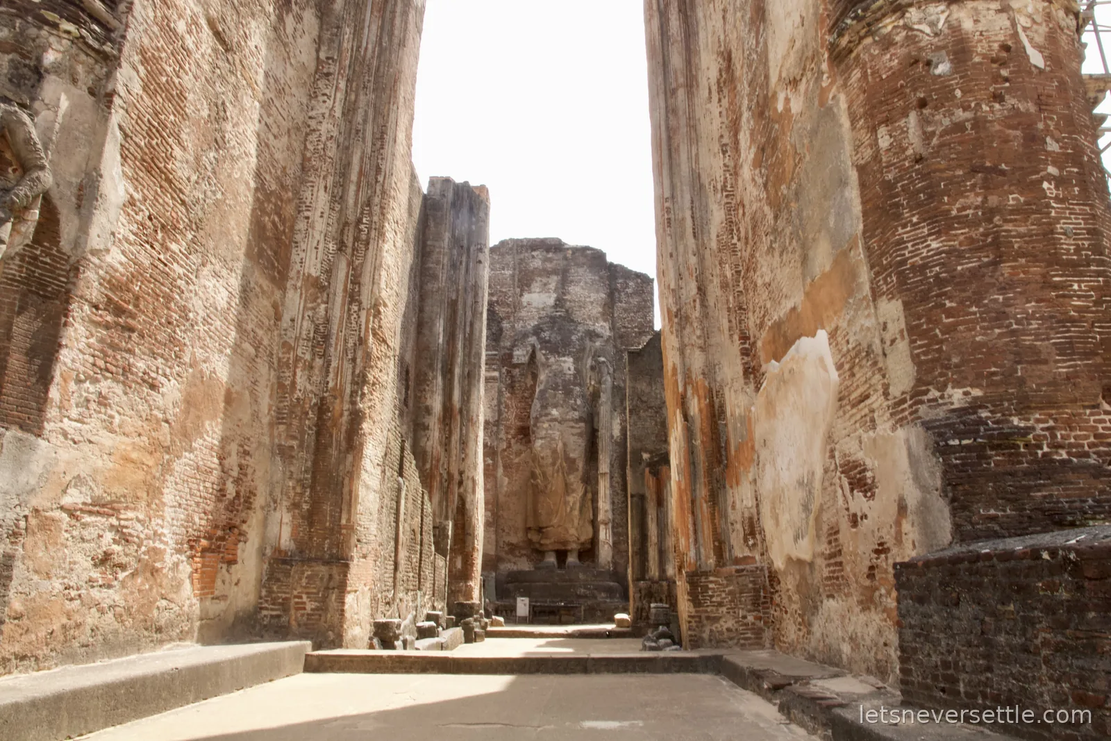 The towering headless standing Buddha inside the brick image house of Lankatilaka at Polonnaruwa, with flower offerings at its feet