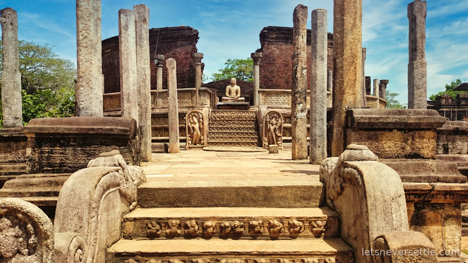 The circular Vatadage at Polonnaruwa: carved steps and stone pillars leading up to a seated Buddha statue under a blue sky