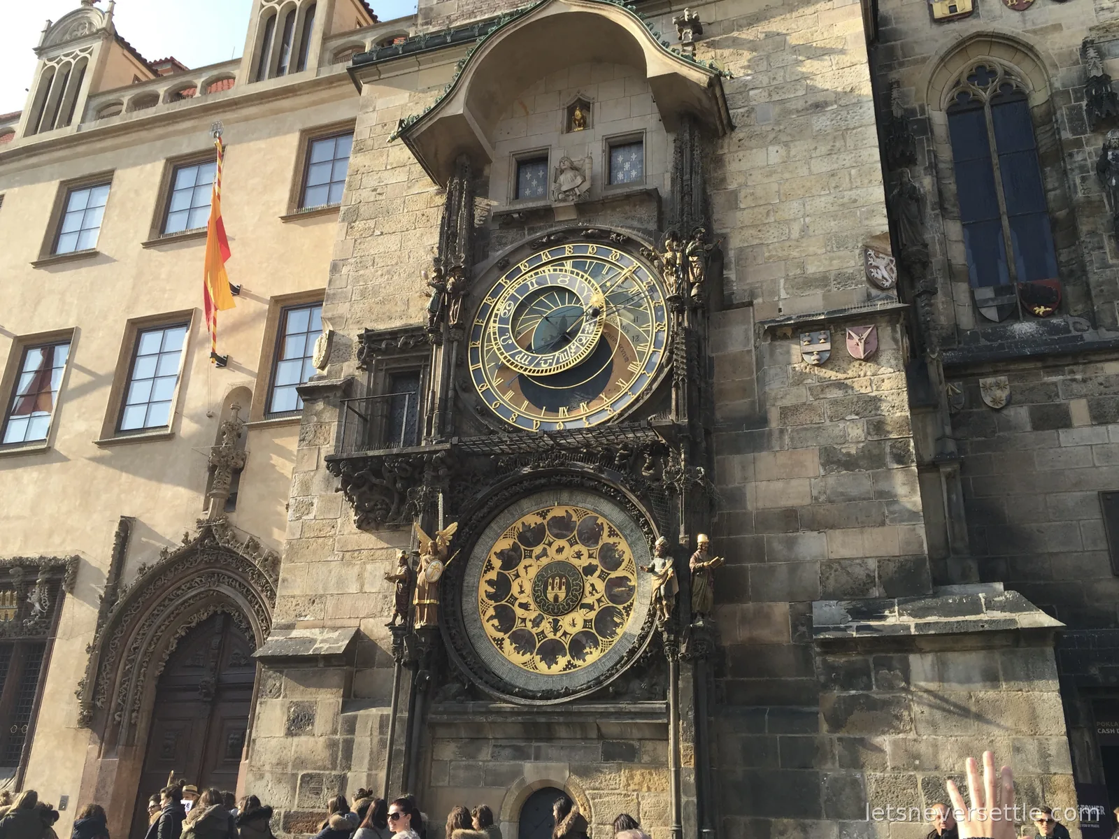 The medieval astronomical clock on the Old Town Hall in Prague, two ornate dials stacked on the stone tower with figures either side