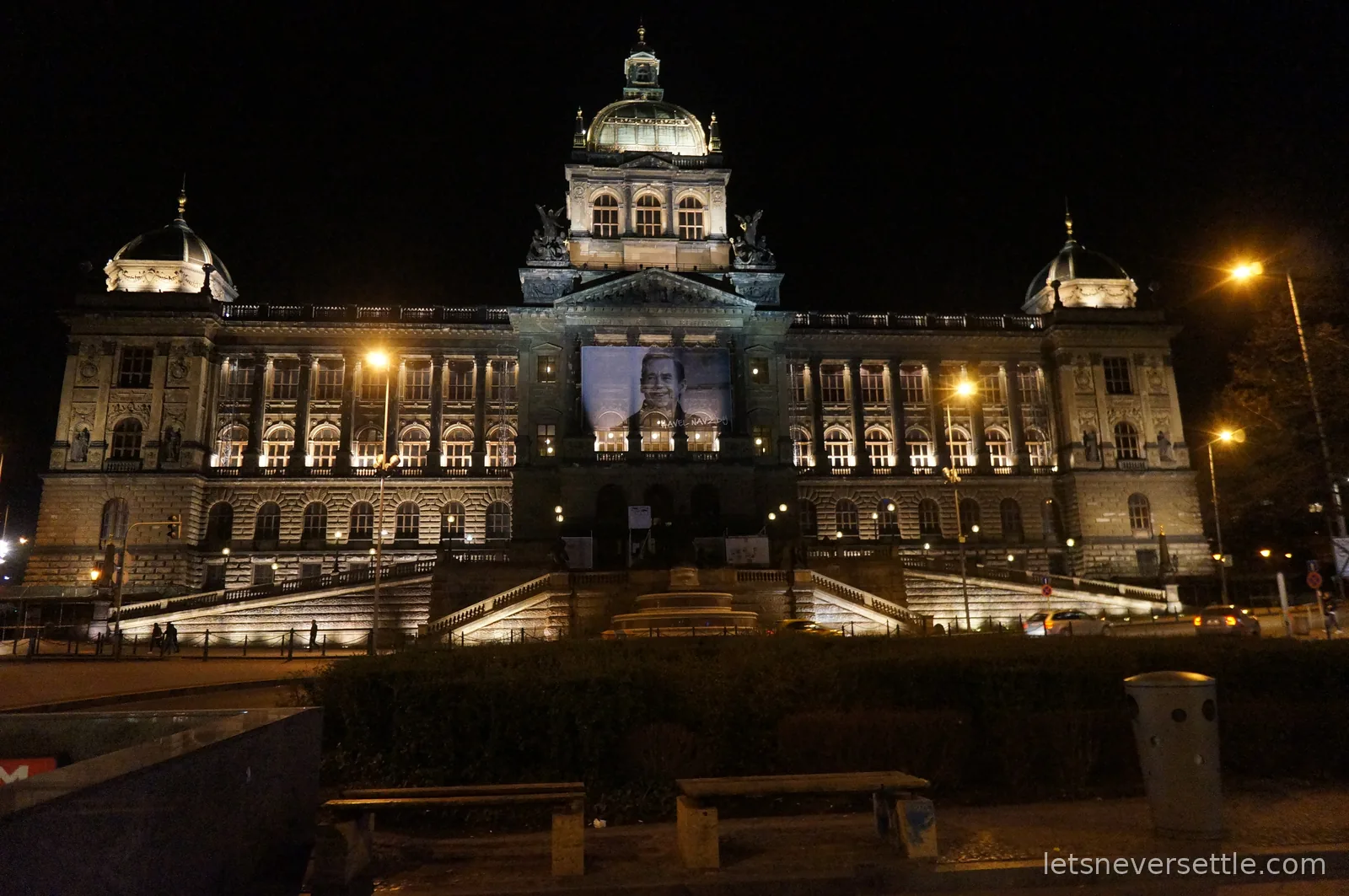 The National Museum in Prague floodlit at night above Wenceslas Square, a large portrait banner of Vaclav Havel hung over the entrance