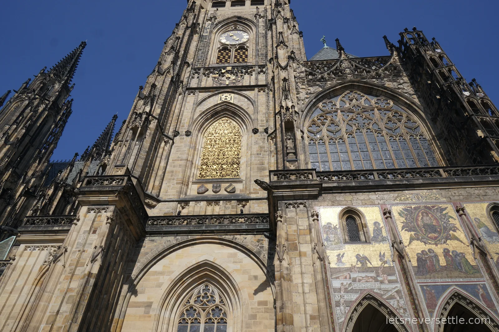 The south face of St Vitus Cathedral at Prague Castle with its clock tower, golden window grille and gilded Last Judgment mosaic