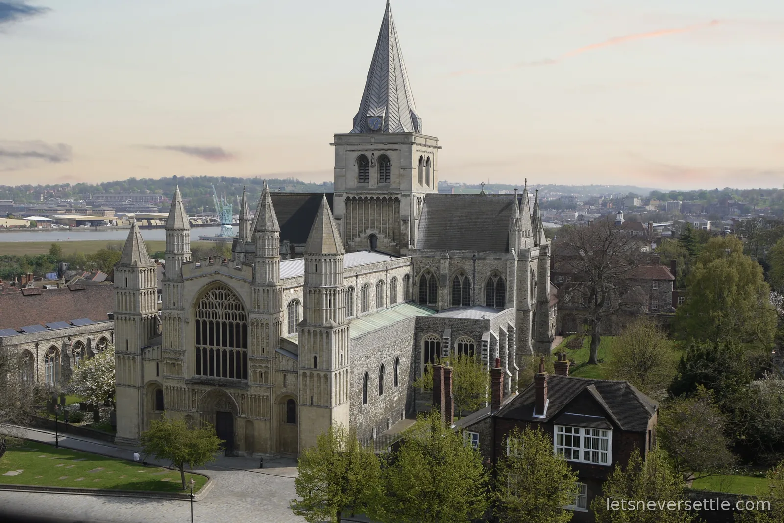 Rochester Cathedral seen from above, from the castle keep, with the River Medway and dockside cranes in the distance