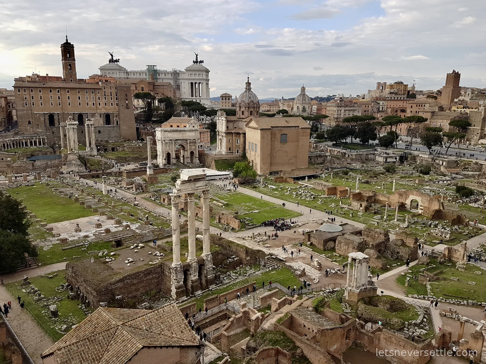 The Roman Forum seen from above, with standing columns, an arch, a domed church and the city rooftops behind