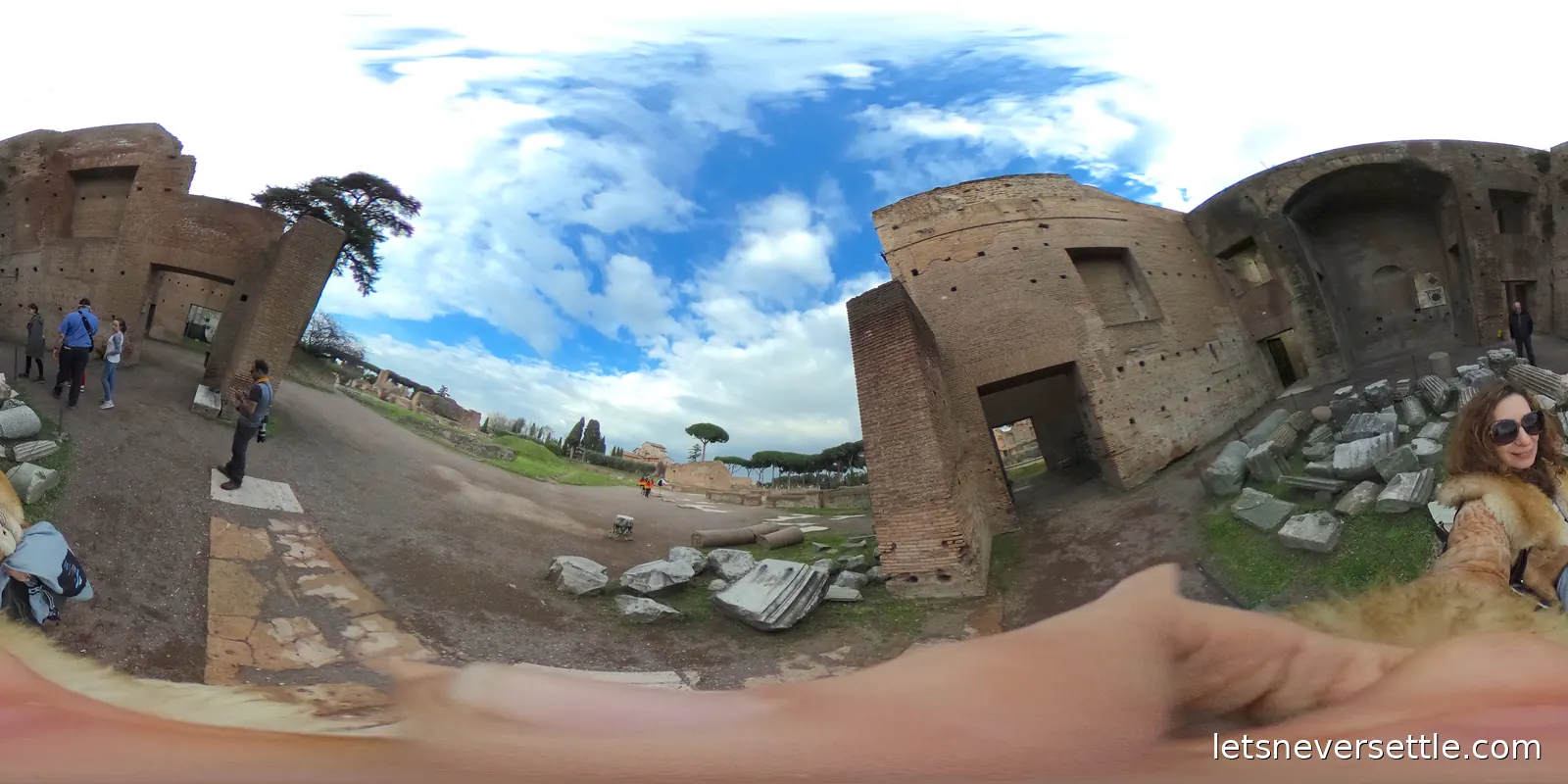Roofless brick walls and scattered marble blocks on the Palatine Hill under a bright sky with umbrella pines