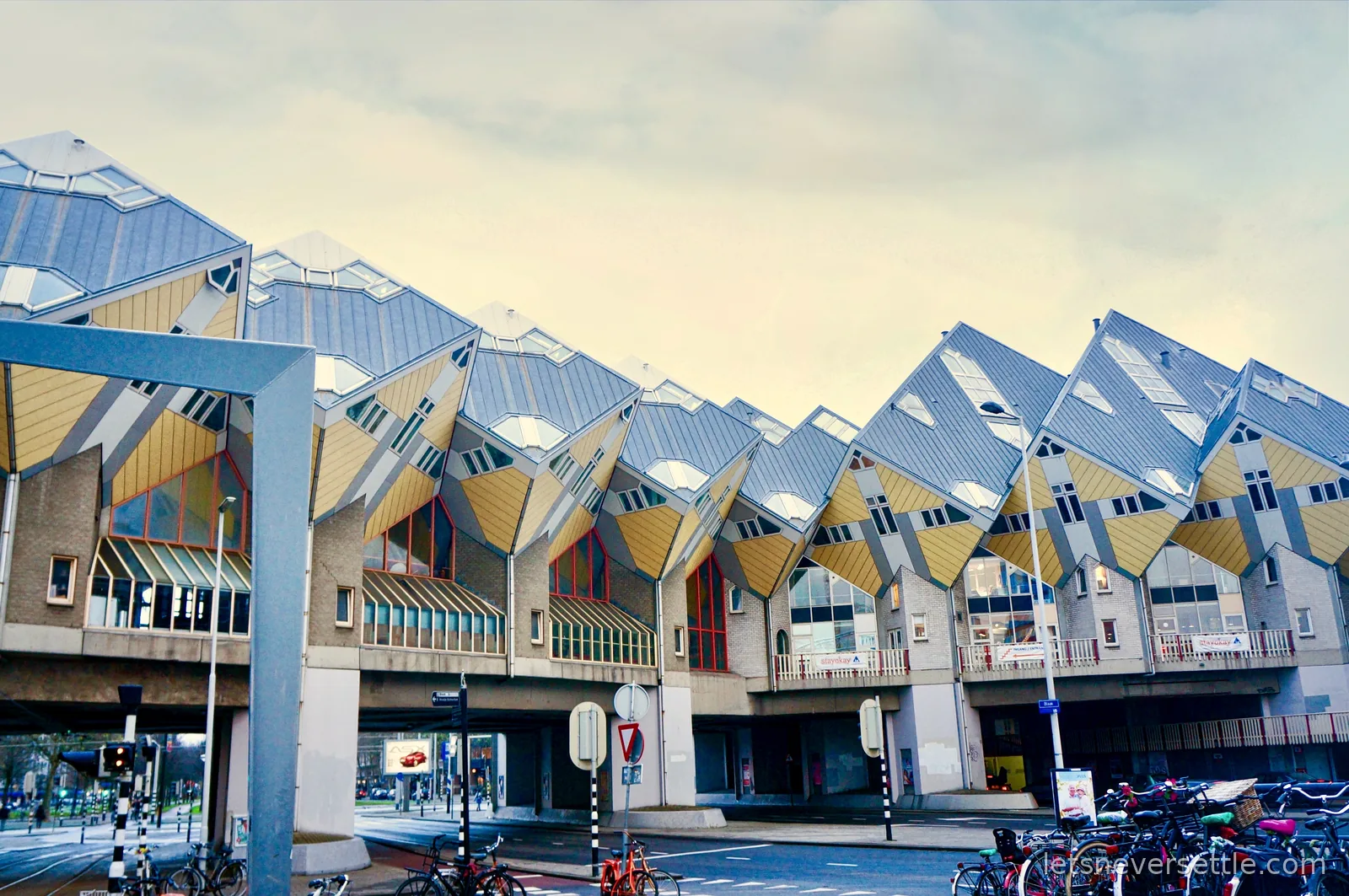 The tilted yellow cube houses at Blaak in Rotterdam, a long row of cubes balanced on concrete stalks above street level