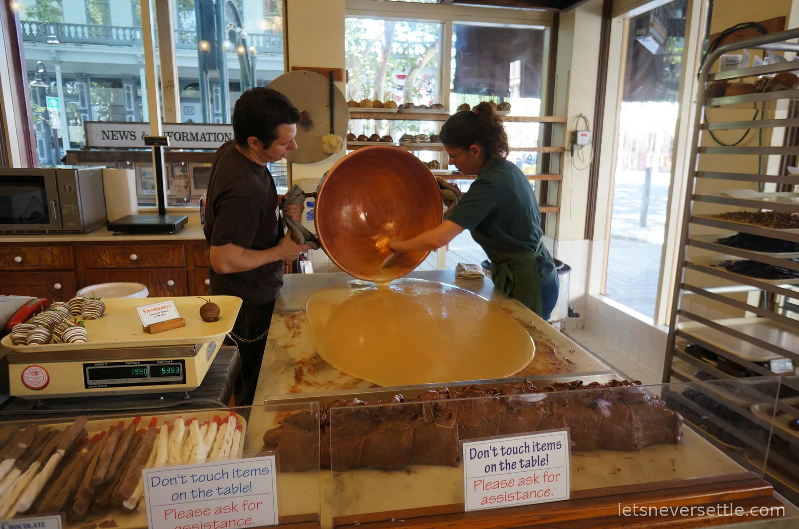 Two confectioners tipping a huge copper kettle of molten candy onto a cooling table in an Old Sacramento sweet shop