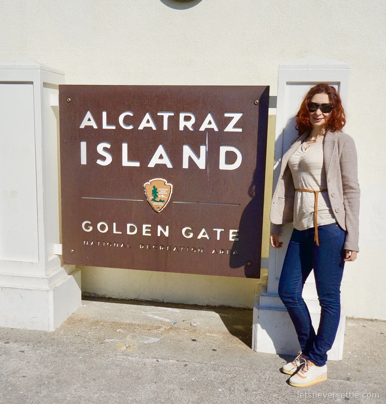 Inga standing beside the rusted Alcatraz Island sign of the Golden Gate National Recreation Area