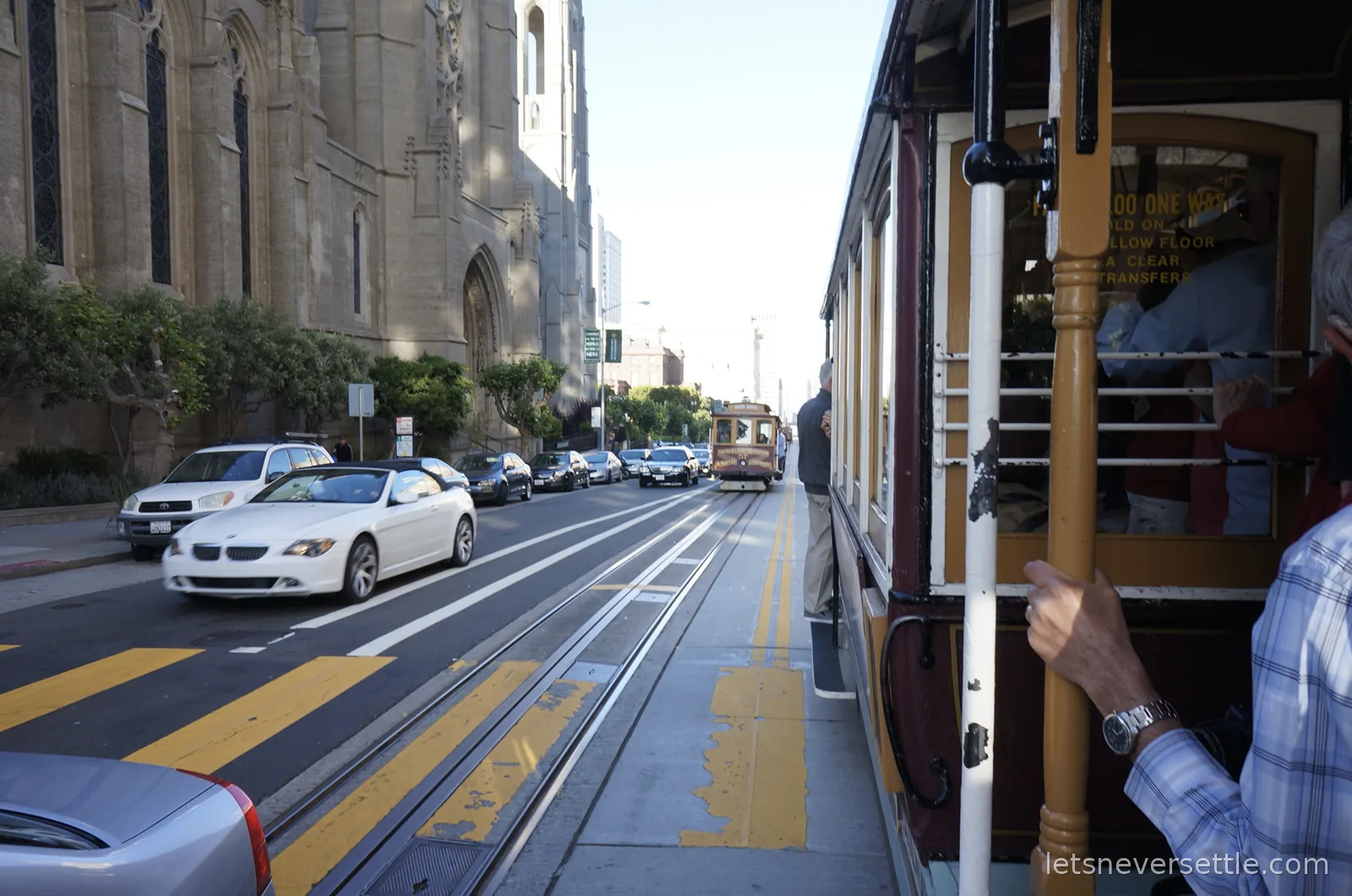 View from a cable car passing the Gothic towers of Grace Cathedral, with another cable car approaching on the tracks ahead